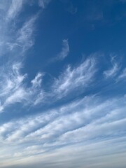 Blue sky with white cirrus clouds on a clear day. Natural background of soft cloudscape