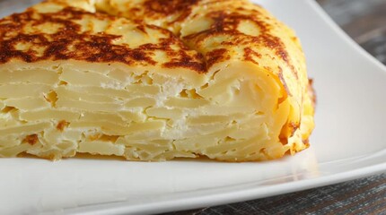 Tortilla Española Delight: A close-up shot captures the golden-brown, exquisitely layered texture of a traditional Spanish tortilla, showcasing its culinary artistry on a simple white plate.