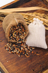 Mixed Organic Rice Grains in Burlap Sacks with Wheat Stalks on Rustic Wooden Background