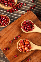 Organic red beans and cranberries in wooden spoons on rustic cutting board for healthy cooking