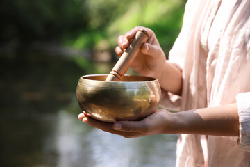 Woman with singing bowl in nature, closeup