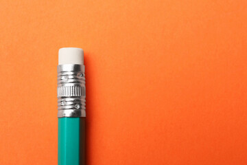 One graphite pencil on orange background, above view. Space for text