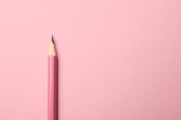 One sharp graphite pencil on pink background, top view. Space for text