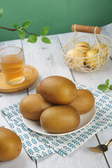 Fresh New Zealand Kiwi Fruits on Rustic Kitchen Table Setting with Wire Basket and Glass