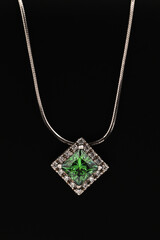 A green gemstone pendant is displayed on a black background