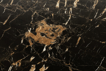 Black marble surface with intricate golden and white veining details showcases natural beauty and elegance for design purposes