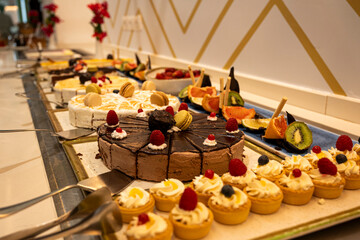 A table full of desserts and fruit, including cakes, tarts, and fruit. The desserts are arranged in a way that makes them look inviting and delicious
