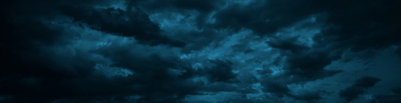 Dramatic sky with heavy clouds. Black dark blue green grey night cloudy sky. Thunderstorm storm rain moonlight wind cyclone hurricane. Ominous frightening fantastic epic. Wide banner. Panoramic.	
