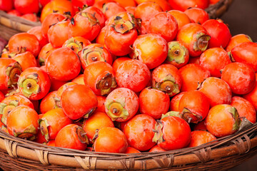 Fresh Orange Persimmons Piled in Wicker Basket - Autumn Harvest Fruit Display