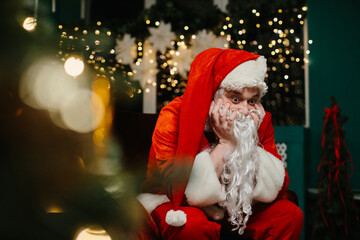 Bored santa claus resting chin on hands near christmas tree