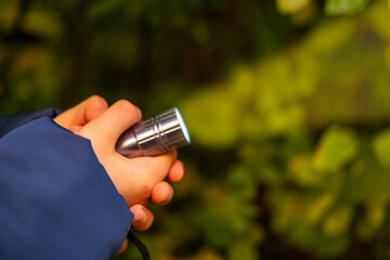 Young person with LED torch in darkness, exploring unknown and symbolizing mystery and survival, Teenager with flashlight in dark, searching for way out, night danger, young explorer