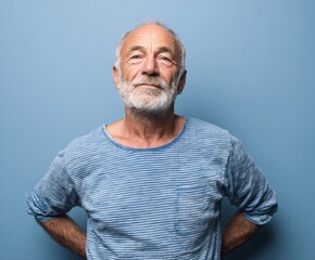 Obraz premium A mature man with a thoughtful expression, positioned against a solid light blue backdrop, displays a serene and composed demeanor.