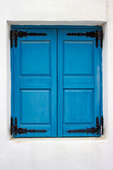 Window with closed shutters painted in traditional blue color i Akrotiri, Santorini, Greece