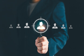 Businessman holding magnifying glass focusing on candidate icon, symbolizing recruitment, human resources, employee selection, target audience, and business hiring strategy.