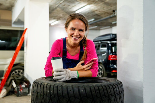 Woman at work. Female auto mechanic taking coffee break in local auto repair shop.