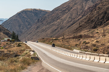 Cars drive along a mountain road in the Boom Gorge in Kyrgyzstan.