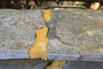 Obraz premium A wall that is plastered. It is paved with stone from above and has a crack that is closed with purpen or foam