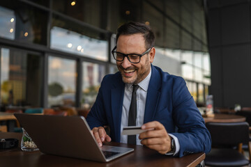 Businessman making online payment using credit card and laptop in cafe