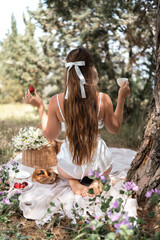 Obraz premium Picnic Woman Strawberry: Back view of lady enjoying peaceful forest picnic, summer day for treats and relaxation.