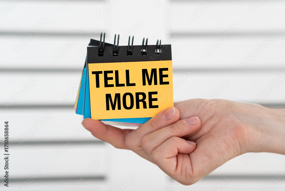 Poster tell me more text on an open notebook in hand on a light background