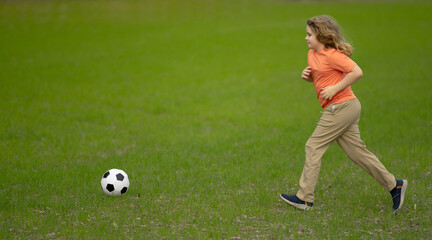 Child playing football in park. Child kicking a football ball on the field. Child running with a football ball. Children playing soccer. Child play football on grass. Summer kids sport. Soccer game.