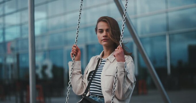 Beautiful young carefree girl swinging on a swing camera tilt to full body