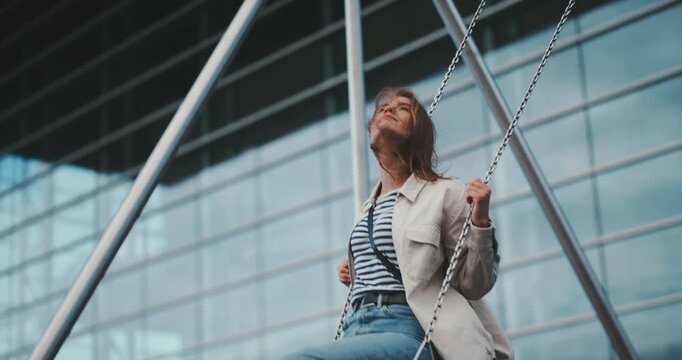 Beautiful young relaxed girl pumping on a swing back and forth motion full body