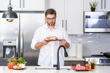 Chef with raw meat beef fillet on kitchen. Handsome man chef cooking raw meat beef. Restaurant menu concept. Beef steak concept. Middle aged man cooking meat, beef steak in kitchen.
