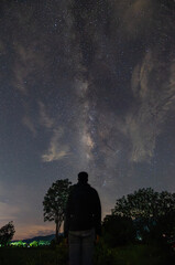 Milky Way shining and silhouette of a man watching in starry night. Space landscape with milky way. Night view. Travel background. Concept.
