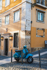 Obraz premium Narrow street corner in historic downtown historic Lisbon, Portugal with storefront and teal scooter