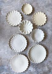 A set of bisque fired handmade and slip cast decorative and scalloped  plates and bowls with a floral theme 