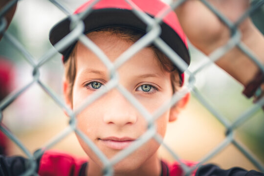 Young boy play baseball on summer day through fence