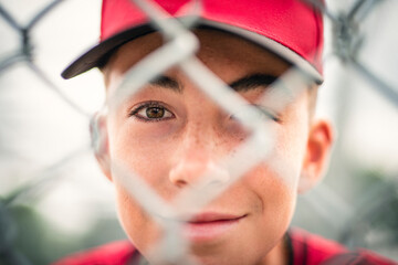 Young boy play baseball on summer day through fence