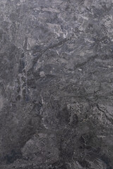 Dark gray textured stone surface with natural patterns and variations in shade for design and decor
