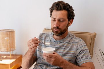 Man enjoying a yogurt on the sofa at home