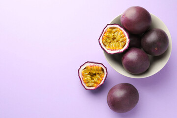 Fresh passion fruits on violet background, flat lay. Space for text