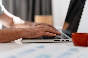 Businessman typing on laptop keyboard in office working on project