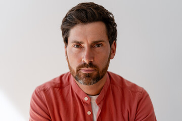 Portrait of confident businessman wearing coral shirt posing on white background