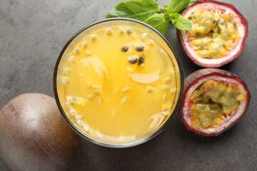 Tasty passion fruit drink with mint and fresh fruits on grey table, flat lay