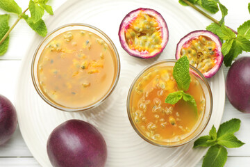 Tasty passion fruit drink with mint and fresh fruits on white wooden table, flat lay