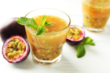 Tasty passion fruit drink and fresh fruits on white wooden table, closeup