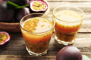 Tasty passion fruit drink and fresh fruits on wooden table, closeup