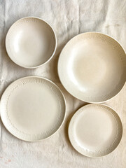 A set of handmade ceramic plates and bowls with a carved edge made from buff stoneware in a matt transparent glaze	