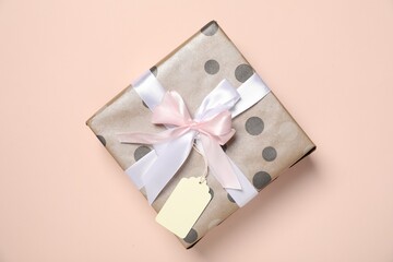 Gift box with blank tag on pale pink background, top view