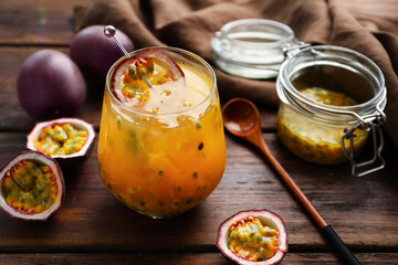 Tasty passion fruit drink in glass and fresh fruits on wooden table, closeup