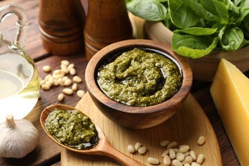 Fresh pesto sauce and ingredients on wooden table, closeup
