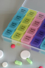 Colorful weekly pill organizer with various pills for daily medication