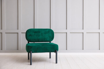 Stylish armchair near gray wall in room. Space for text