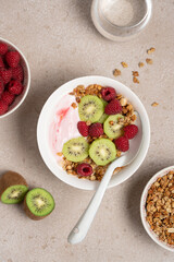 Top View of Raspberry Yogurt in White Bowl with Fresh Kiwi Topping and Ripe Raspberries on Beige Background, Healthy Dessert and Breakfast Concept