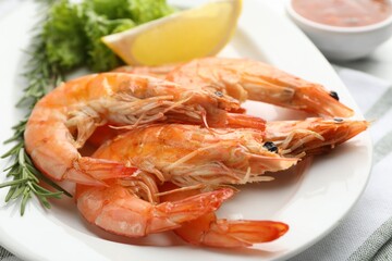 Tasty grilled shrimps served with lemon, lettuce and rosemary on table, closeup. Delicious seafood dish